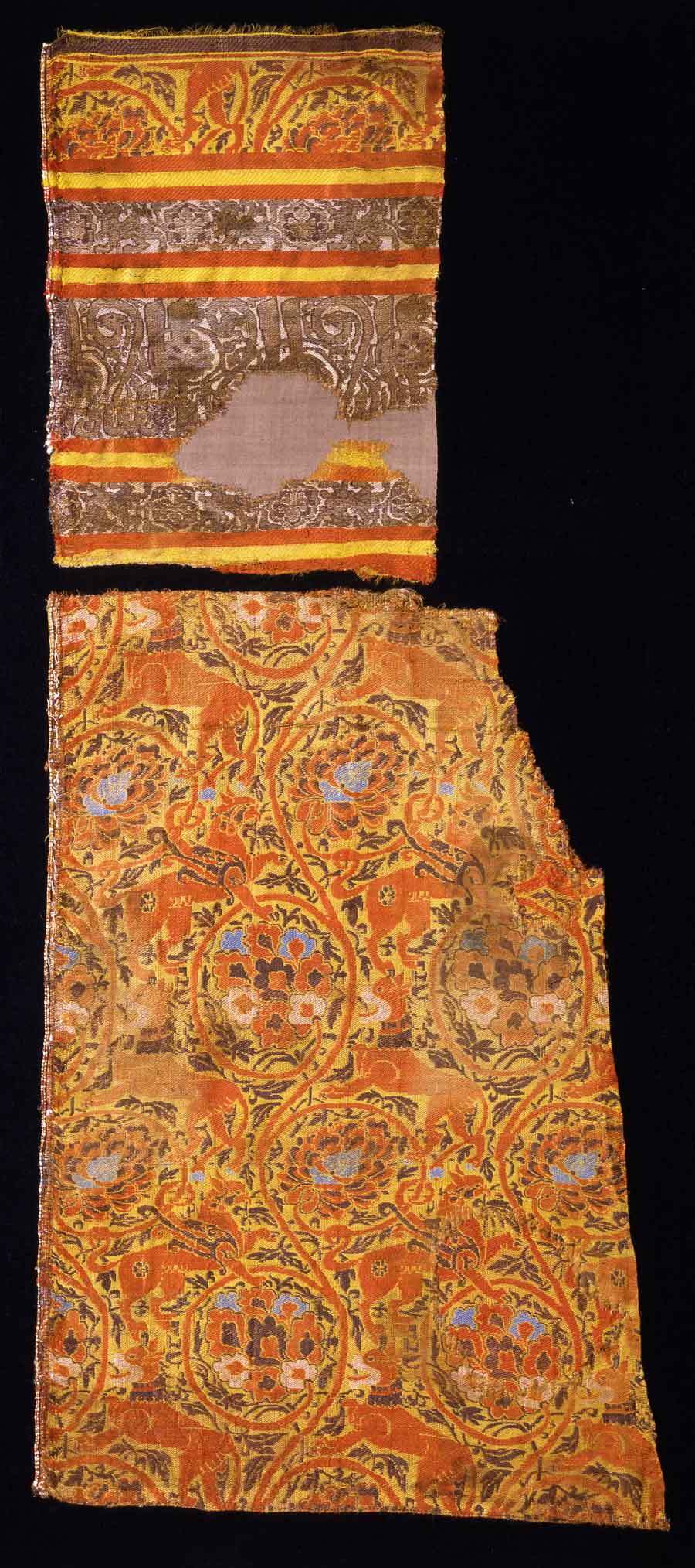 Silk textile with animals and mythical creatures in vine scrolls, Central Asia or Eastern Iran; 13th century <br> Textiles woven in or near Central Asia have shown the influence of both East and West since ancient times, and this is also true of this vibrant silk. The inscription frieze at the top is based on Arabic, and both the griffins and the lions have a clear Western look. The lively arabesque-like swirling vines in two layers (one red, the other brown) point in both directions, while the heavy, colorful flowerheads are clearly inspired by the Chinese lotus and peony. The frieze is a good example of how calligraphy and vegetal ornamentation were merged into an artistic whole. In contrast to the somewhat older bowls, where letters develop into plants, these end in animal heads of different types.