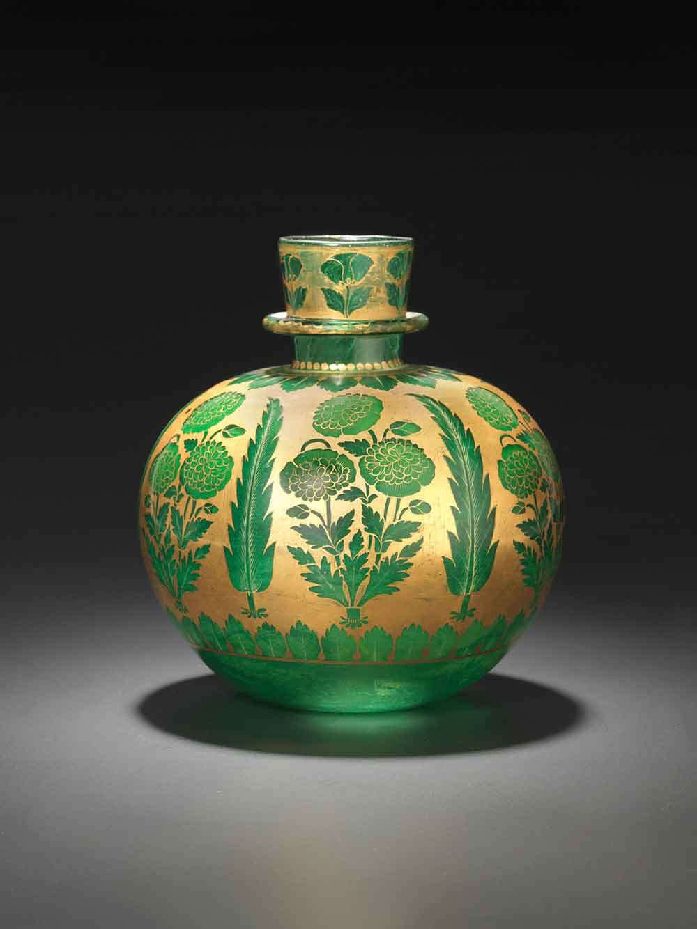 Water pipe (huqqa), green glass with poppies, India, Mughal; beginning of 18th century <br> The brilliant emerald-green glass of this water pipe is the ground color for the six poppies and six cypresses painted in reserve on a golden ground. Details are painted in gold, and inside is a layer of enamel paint to create depth in the composition. The asymmetrically arranged poppies of different kinds on the neck seem quite natural, though a little stiff. <br> Several of the Great Mughals were habitual users of opium, derived from the opium poppy, papaver somniferum. It is no coincidence that the poppy was often found as a decoration on water pipes, which could be used to smoke opium mixed with tobacco.