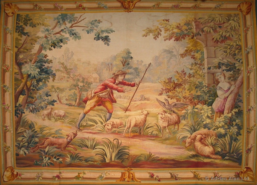 A FINE AUBUSSON PASTORAL TAPESTRY DEPICTING A SHEPHERD AND SHEPHERDESS IN A PICTURESQUE LANDSCAPE C. 1900, FRANCE
