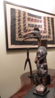 A framed Pacific tapa cloth hangs above African sculptures of James Willis, African art