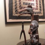 A framed Pacific tapa cloth hangs above African sculptures of James Willis, African art