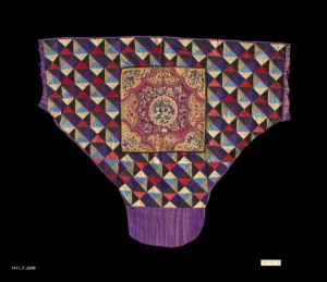 Baby Carrier, China Zhuang, 20th Century. 3' x 2' 6 3/4" (91.4 x 78.1cm); Cotton, silk; quilting and appliqué, embroidery in silk on ceter panel. Baby carrier with a field of multi-colored tabby woven cotton fabrics, cut into triangles and quilted. Center panel formed of appliquéd satin elements in scalloped pattern, and then embroidered in silk. Cloth ties are cut off. Roger Hollander Collection - Primary collection