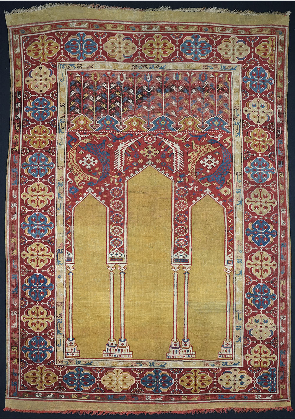 Transylvanian’ coupled-column prayer rug, Ushak region, west Anatolia, early 17th century. 1.30 x 1.83 m (4' 3" x 6' 0"). Warp: natural ivory wool, spun Z2S, dyed light red at the lower end, slightly depressed; weft: wool, spun Z, two shoots between each row of knots, generally ivory or dyed light red, occasionally light blue; knots: wool, symmetrical (Turkish), ca. 50 vertical x 38 horizontal, average density ca. 1,900/dm2 = ca. 123/in2; colours: (9) ochre yellow, light yellow, pinkish beige, ivory, red, light blue, medium blue, dark blue, dark brown (corroded). Arkas Collection, Izmir